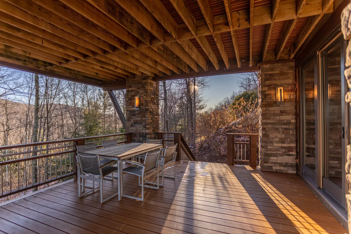 An outdoor dining area with a large table beneath wooden beams, surrounded by nature. The peaceful setting is ideal for post-adventure relaxation, outdoor meals, and enjoying serene evenings with the group.