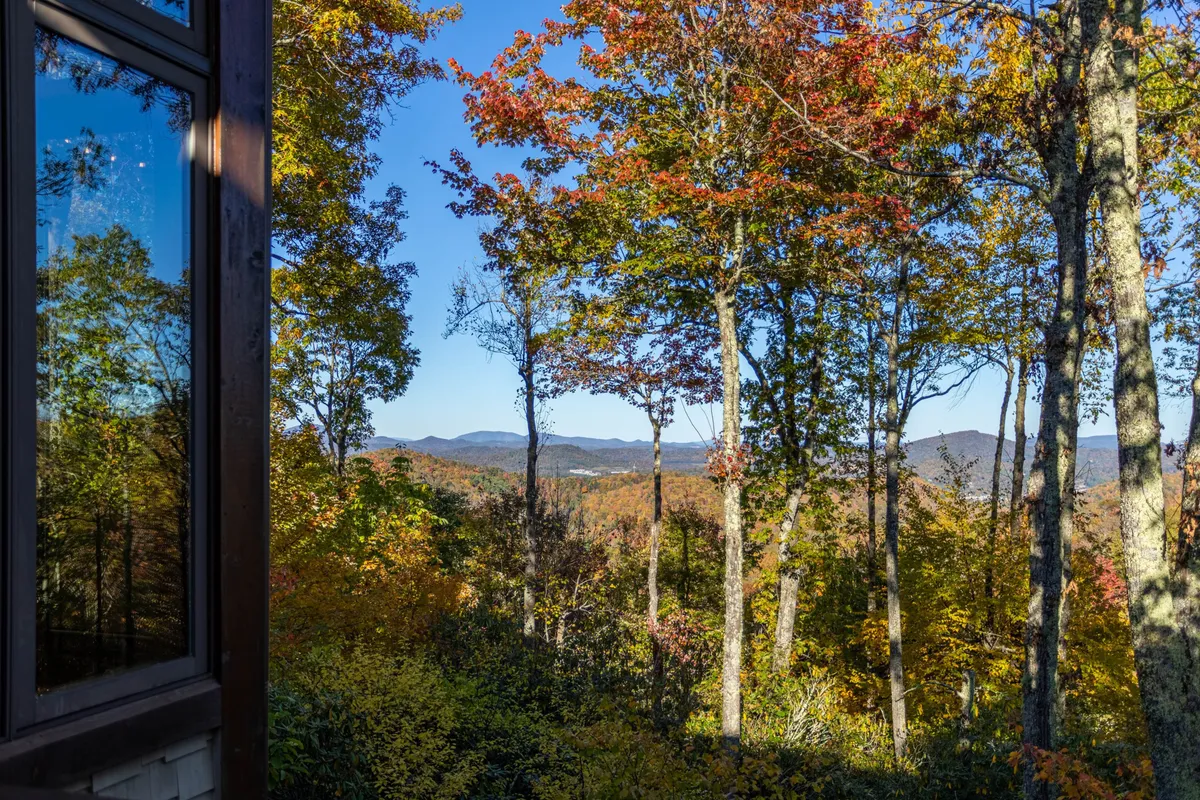 Looking out from the home, this image reveals breathtaking long-range mountain views and vibrant autumn foliage, with reflections in the window adding depth. It evokes the feeling of waking up to stunning vistas or enjoying a quiet morning on the deck.