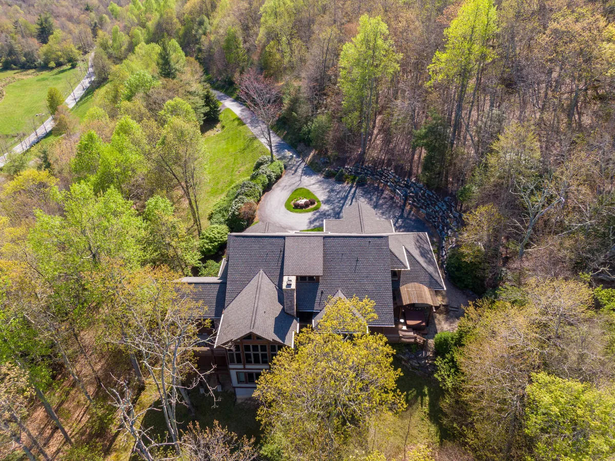 An inviting exterior shot of the main house, accentuated by a circular driveway and lush greenery. The view emphasizes the ease of access for multiple vehicles and hints at ample space for group arrivals and departures.